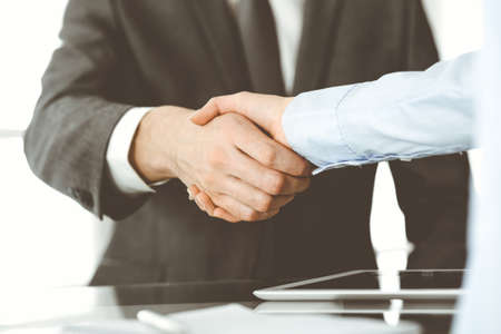 Unknown business man and woman are shaking hands finishing contract signing, close-up. Business and handshake conceptの写真素材