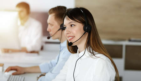 Asian woman working at customer service office. Business concept. Group of diverse operators at work in sunny call center.の写真素材