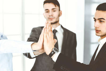 Business people group showing teamwork, joining hands and giving five to each other in modern...