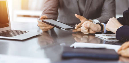 Unknown businessman using tablet computer and working together with his colleague while sits at the...