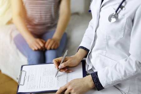 Close-up of woman-doctor and patient discussing current health examination while sitting indoors. Stay at home concept during Coronavirus pandemic and self isolation quarantine. Covid 2019の写真素材