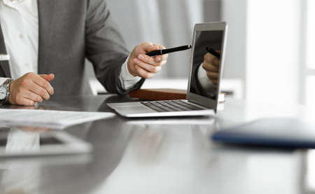 Unknown business people using laptop computer at the desk in modern office. Businessman or male...