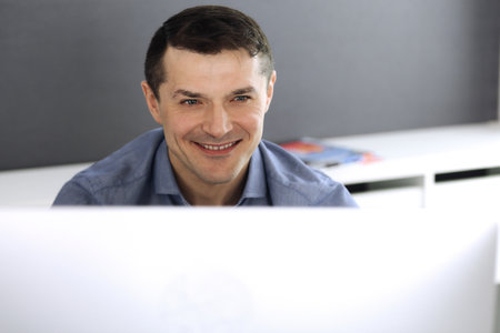 Businessman working with computer in modern office. Headshot of male entrepreneur or company...