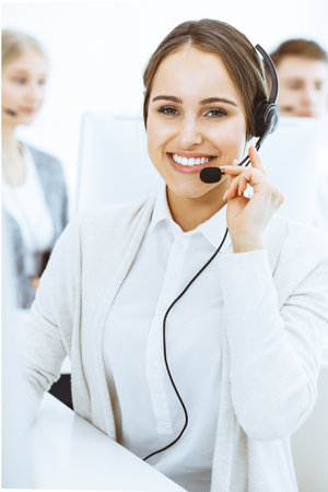 Call center. Group of diverse operators at work. Beautiful woman in headset communicating with customers of telemarketing service. Business conceptの写真素材