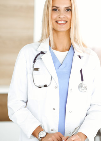 Doctor woman controls medication history records and exam results while using clipboard in sunny hospital . Medicine and healthcare conceptの写真素材