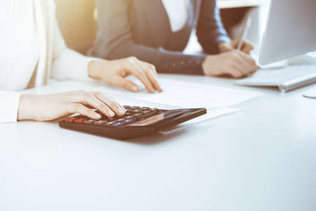Accountant checking financial statement or counting by calculator income for tax form, hands...