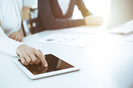 Businesswoman pointing at tablet computer screen while giving presentation to her female colleague....