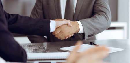 Unknown business people are shaking hands after contract signing in modern office, close-up. Handshake as successful negotiation endingの写真素材