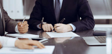 Unknown business people working together at meeting in modern office, close-up. Businessman and woman with colleagues or lawyers discussing contract at negotiationの写真素材