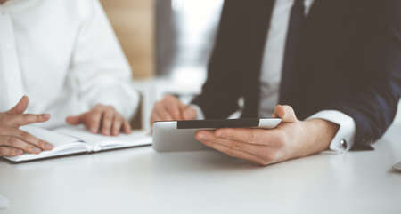 Unknown business people using tablet computer in modern office. Businessman or male entrepreneur is...