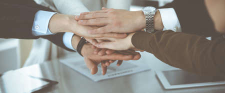 Business people group showing teamwork and joining hands or giving five in modern office. Unknown...