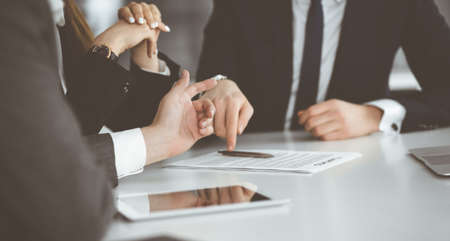 Unknown businessmen and woman sitting, working and discussing questions at meeting in modern office, close-upの写真素材