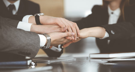 Unknown business people group joining hands in modern office. Businessmen and women making circle with their hands as a team, close-upの写真素材