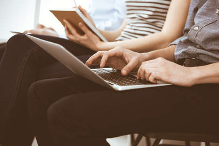 Group of casual dressed business people working at meeting or conference, close-up of hands....