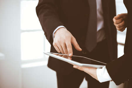 Businessman and woman using tablet computer for discussing questions in office. Partners or colleagues at meeting. Business cooperation conceptの写真素材