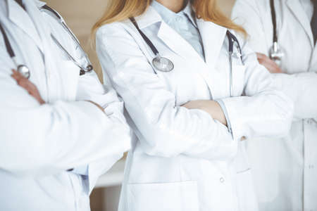 Group of unknown doctors standing as a team with arms crossed in hospital office, close-up. Medical help, insurance in health care and medicine conceptの写真素材