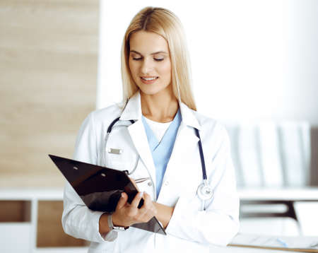 Woman-doctor controls medication history record and medical exam results. at black clipboard. Medicine conceptの写真素材