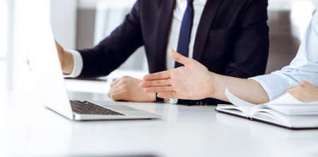 Unknown business people using laptop computer at the desk in modern office. Businessman or male entrepreneur is working with his colleague. Teamwork and partnership conceptの写真素材