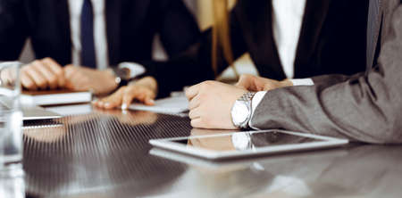 Unknown businessmen and woman sitting, using laptop computer and discussing questions at meeting in modern office, close-upの写真素材