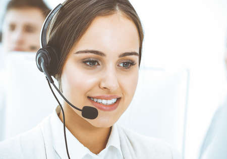 Call center. Group of diverse operators at work. Beautiful woman in headset communicating with...
