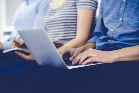 Group of casual dressed business people working at meeting or conference, close-up of hands. Businessman using laptop computer. Teamwork or coaching conceptの写真素材