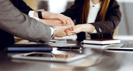 Unknown business people group joining hands in modern office. Businessmen and women making circle with their hands as a team, close-upの写真素材
