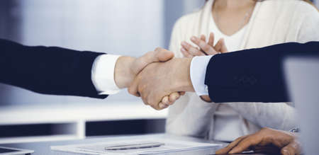 Business people shaking hands after contract signing in modern office. Teamwork and handshake...