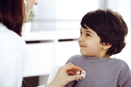 Doctor-woman examining a child patient by stethoscope. Cute arab boy at physician appointment....