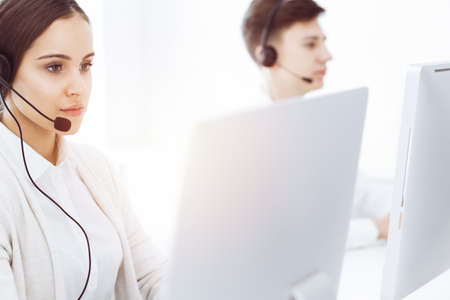 Call center in sunny office. Group of diverse operators at work. Beautiful woman in headset...