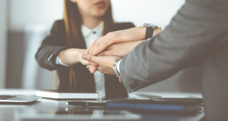 Unknown business people group joining hands in modern office. Businessmen and women making circle with their hands as a team, close-upの写真素材
