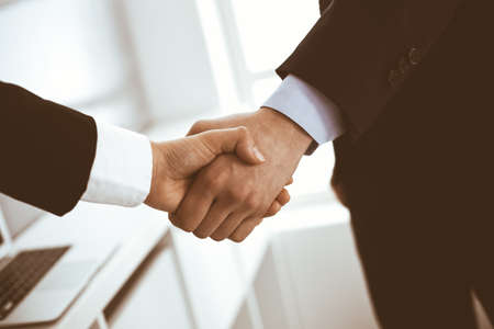 Businessman and woman shaking hands in office. Concept of handshake as success symbol in businessの写真素材