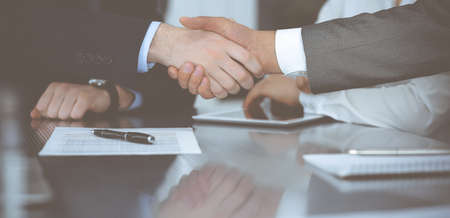 Handshake as successful negotiation ending, close-up. Unknown business people shaking hands after contract signing in modern officeの写真素材