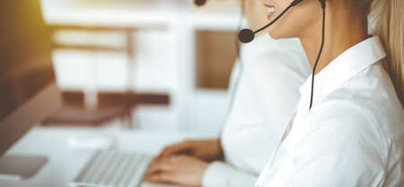 Unknown female customer service representative iconsulting clients online using headset.close-up....