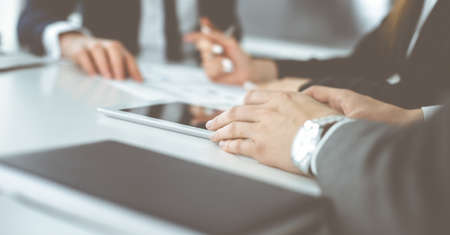 Unknown businessmen and woman sitting, working and discussing questions at meeting in modern office,...