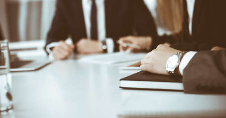 Unknown businessmen and woman sitting, working and discussing questions at meeting in modern office,...