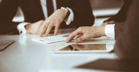 Unknown businessmen and woman sitting, working and discussing questions at meeting in modern office, close-upの写真素材
