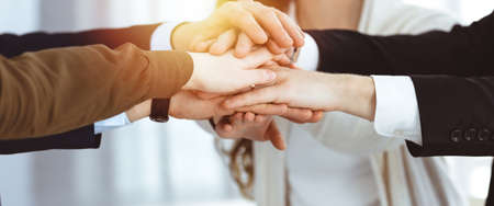 Business people group showing teamwork and joining hands or giving five in sunny office. Unknown businessman and women making circle with their handsの写真素材