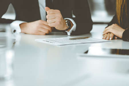 Unknown businessmen and woman sitting, working and discussing questions at meeting in modern office,...