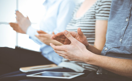 Business people clapping at meeting or conference, close-up of hands. Group of unknown businessmen and women in modern white office. Success teamwork, corporate coaching and applause conceptの写真素材