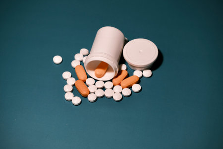 white and orange antiretroviral therapy pills for treatment of HIV scattered next to an open package. on a green table. World AIDS Day concept. Healthcare and medicine.の写真素材