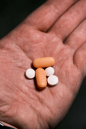 white and orange antiretroviral therapy pills for treatment of HIV in hand. Dolutegravir, Abacavir, Lamivudine. World AIDS Day concept. Healthcare and medicine. Tablets and medication. Horizontal pic.の写真素材