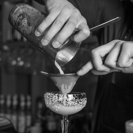 The bartender makes a cocktail of coconut and ice. Macro, black background, hand, white.