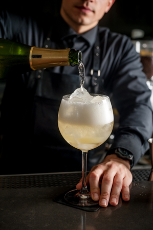 a bartender makes a summer cocktail of lime and ice. Macro, black background, hand, yellow, drops on glass, bubbles.の写真素材