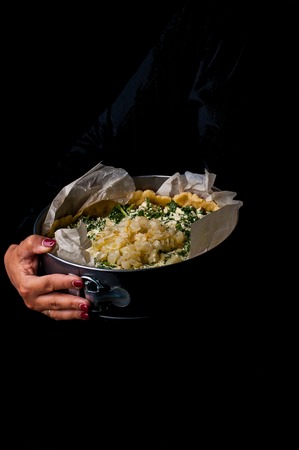 Onion spinach cake. A shape with a cake in his hands on a black background.の写真素材