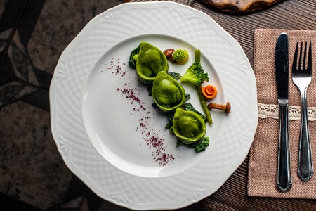 Green Ravioli with quail egg. A Halloween Feast. Black brick wall background and wooden tableの写真素材