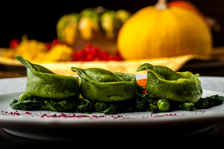 Green Ravioli with quail egg. A Halloween Feast. Black brick wall background and wooden tableの写真素材