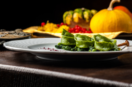 Green Ravioli with quail egg. A Halloween Feast. Black brick wall background and wooden tableの写真素材