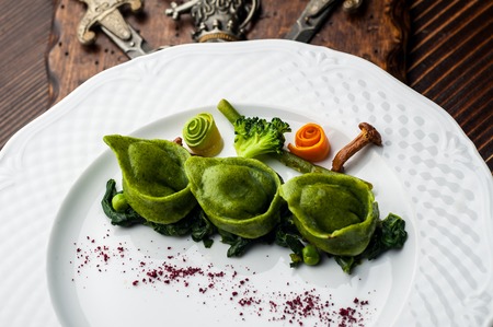 Green Ravioli with quail egg. A Halloween Feast. Black brick wall background and wooden tableの写真素材