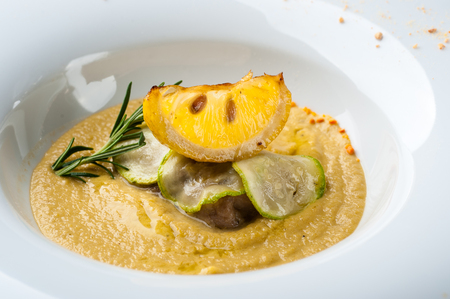 Pumpkin cream soup with fish som. A dish at a restaurant for Halloween celebrations. Black background, brick wall and wooden tableの写真素材