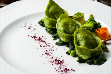 Green Ravioli with quail egg. A Halloween Feast. Black brick wall background and wooden tableの写真素材